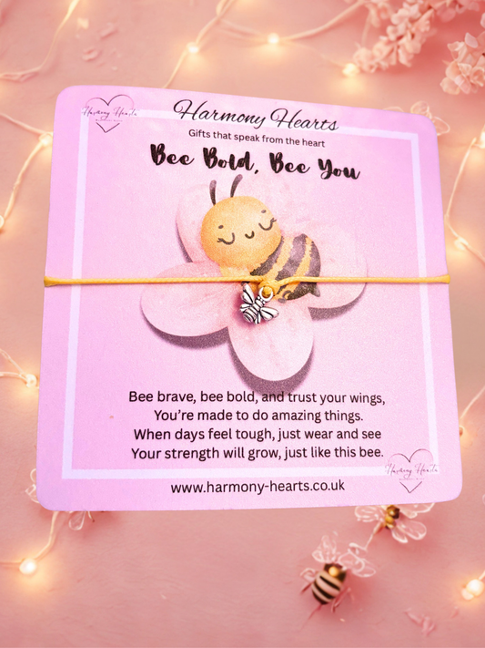 Yellow cord bracelet with silver bee charm on a Pink card with a bee illustration and motivational message on a pink background with fairy lights.