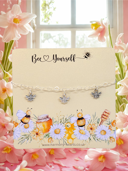 Bee-themed bracelet with silver bee charms set on a decorative card with flowers in the background