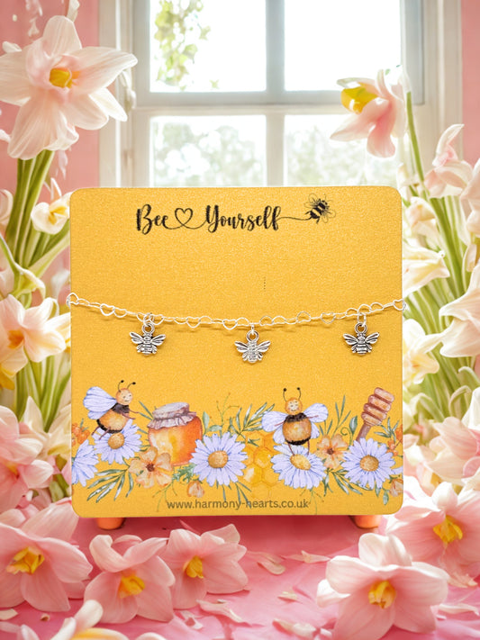 Bracelet with bee-themed charms on a decorative card with floral background