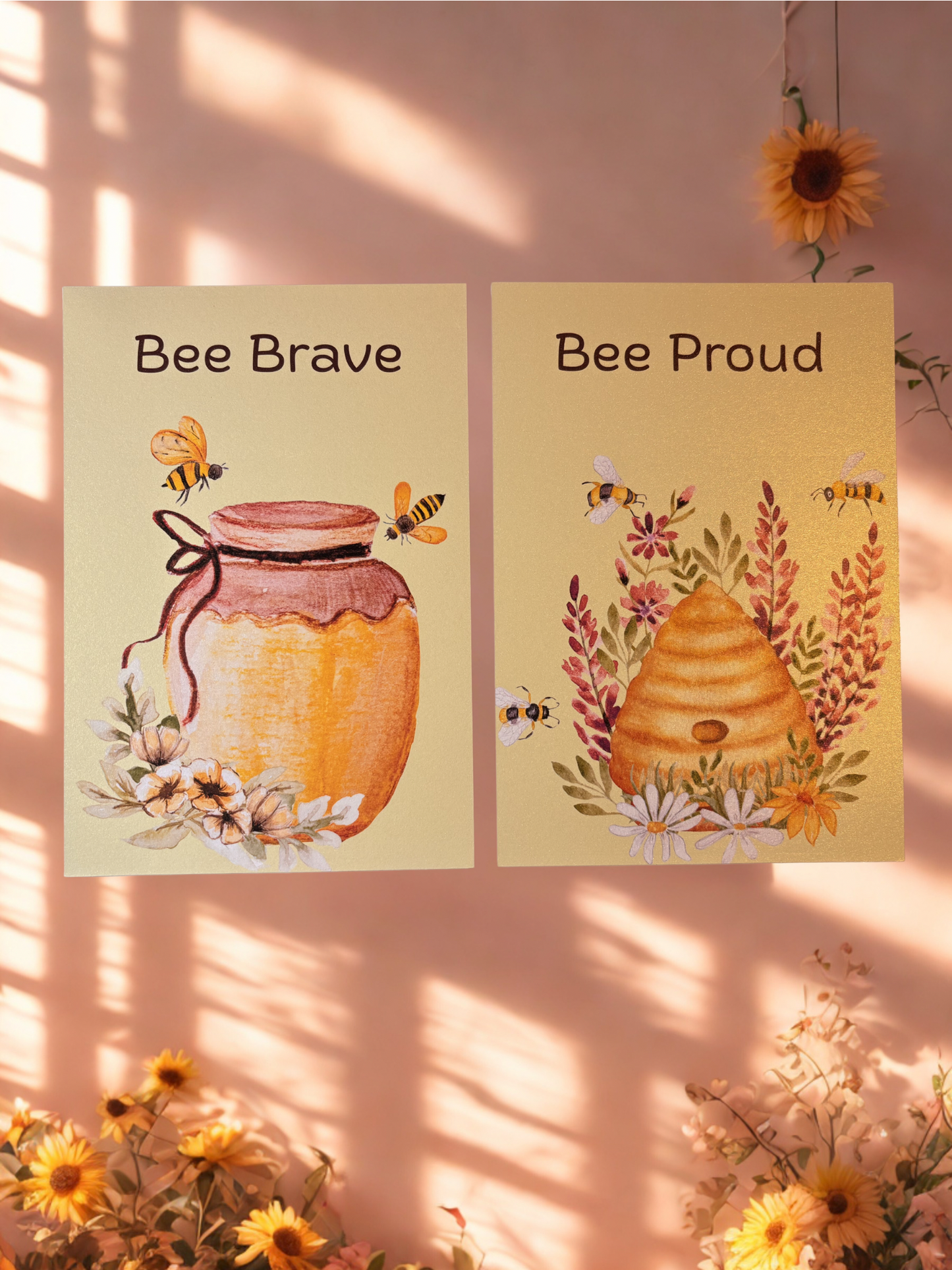 Two motivational prints with bee-themed illustrations and text on a pink background.