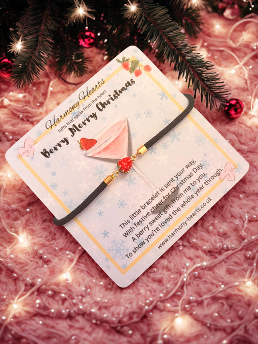 Bracelet with a strawberry charm on a card with Christmas decorations in the background