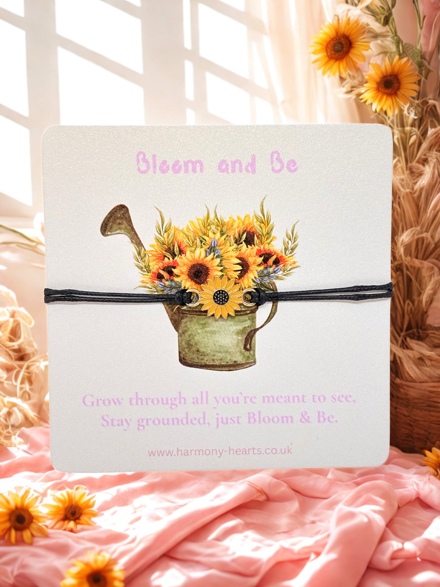 Cord sunflower bracelet on a branded card with sunflower design and text 'Bloom and Be' on a soft pink background.