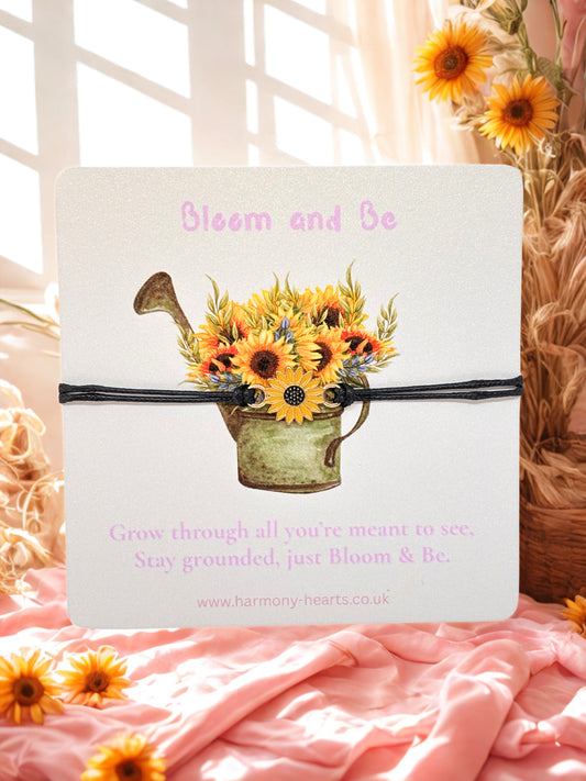 Cord sunflower bracelet on a branded card with sunflower design and text 'Bloom and Be' on a soft pink background.