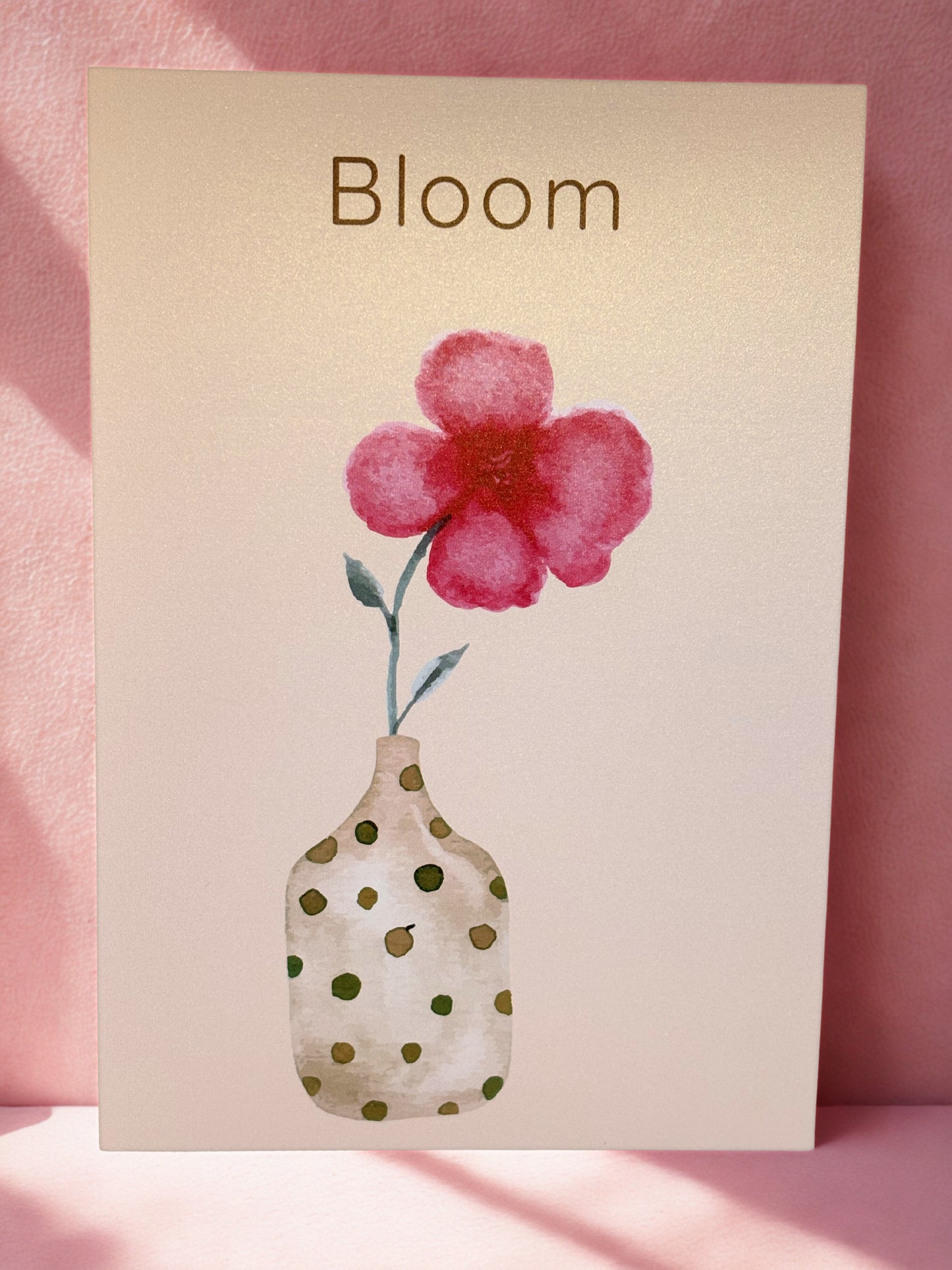 print with a pink flower illustration and 'Bloom' text on a pink background