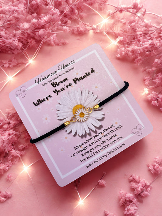 Daisy bracelet on a card with pink flowers and lights in the background