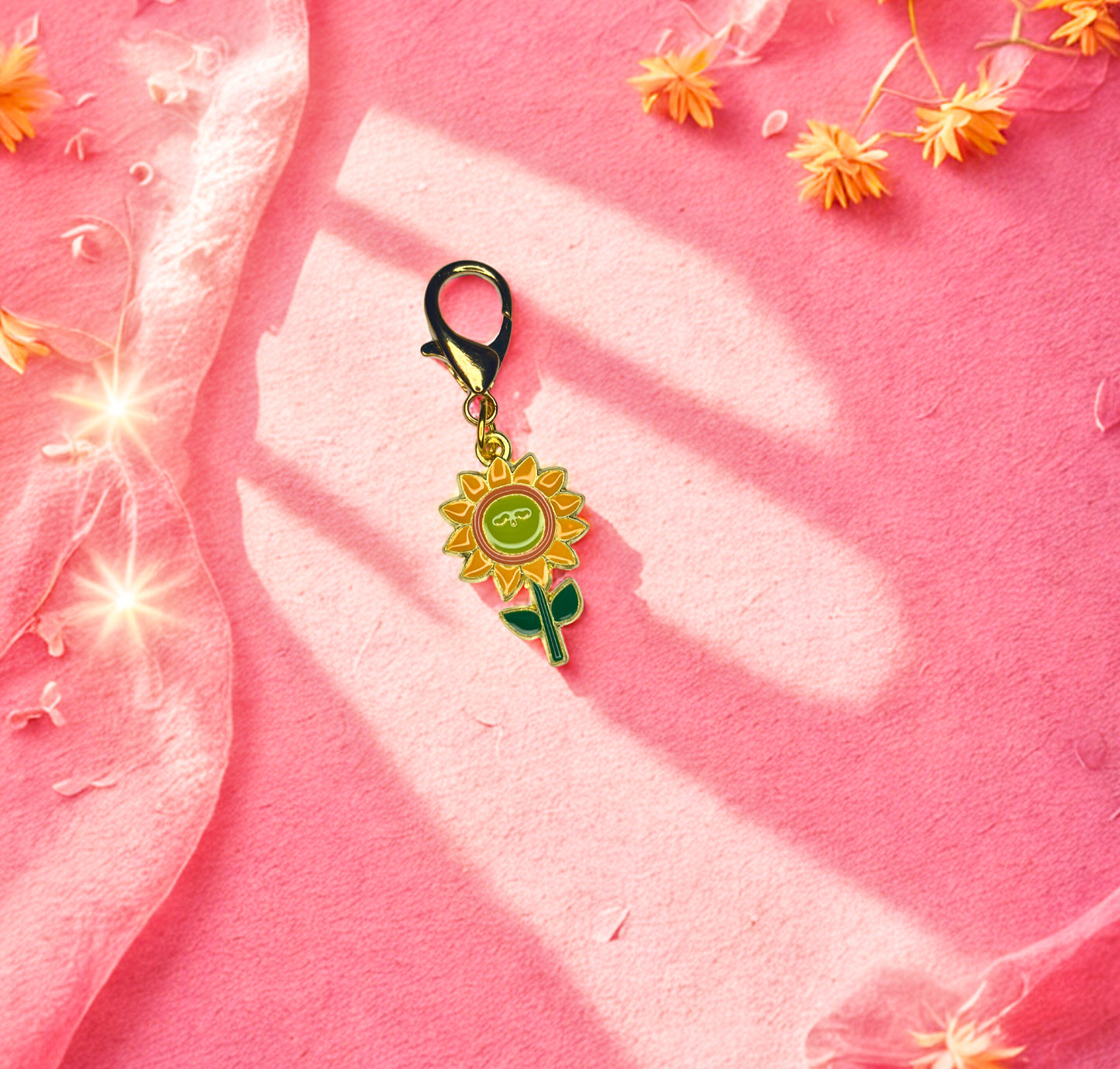 Sunflower-shaped keychain on a pink fabric background with flowers.