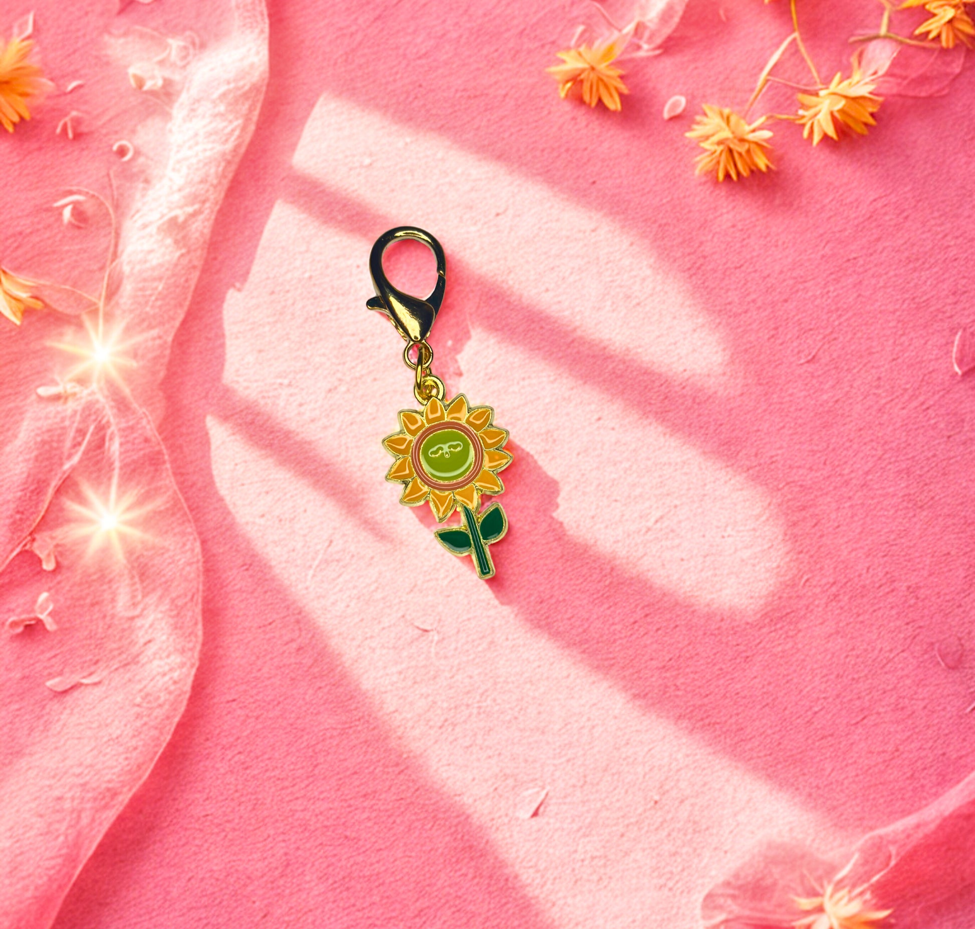 Sunflower-shaped keychain on a pink fabric background with flowers.