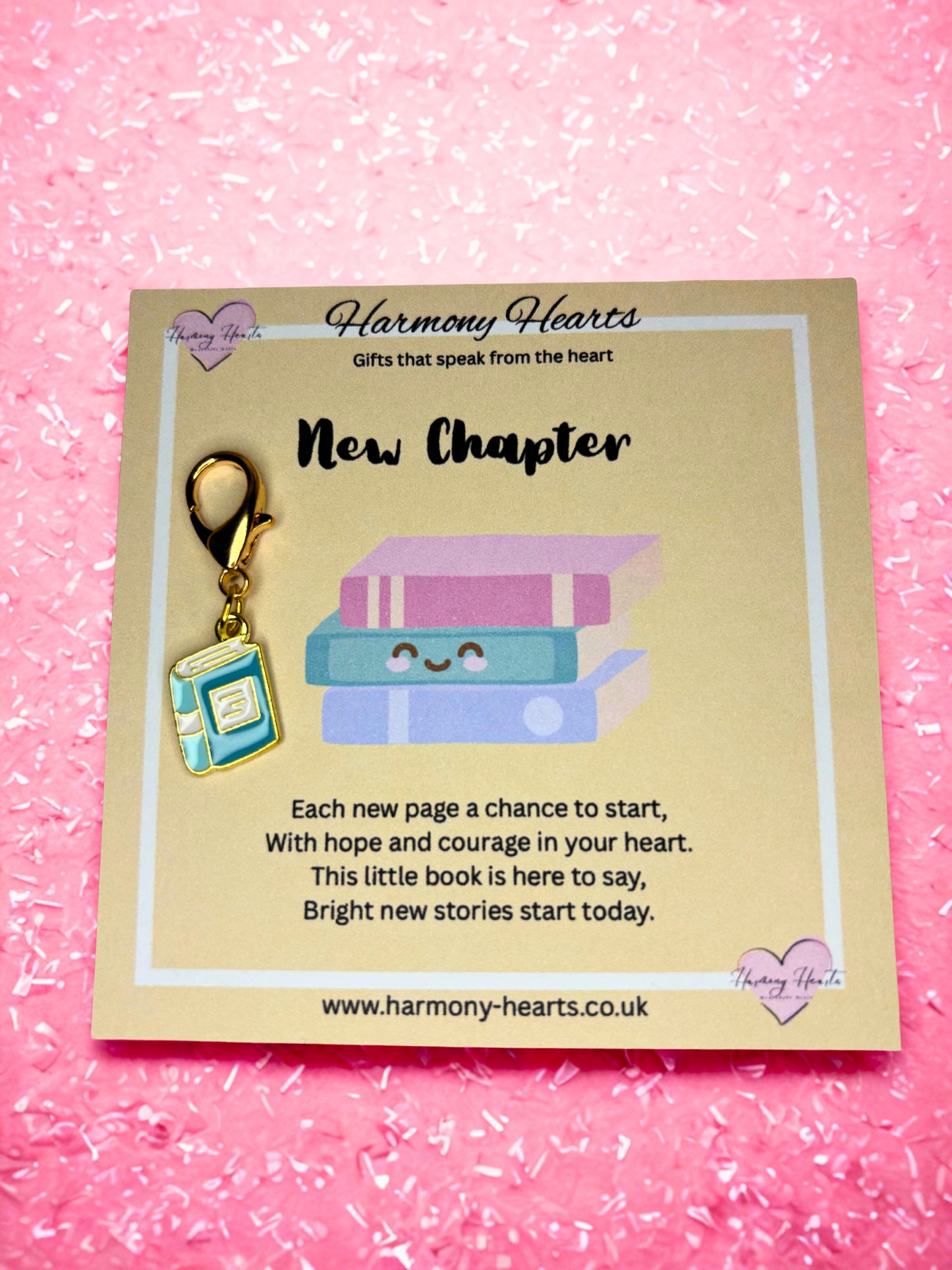 Book-shaped keychain on a 'Harmony Hearts' card with text on a pink background