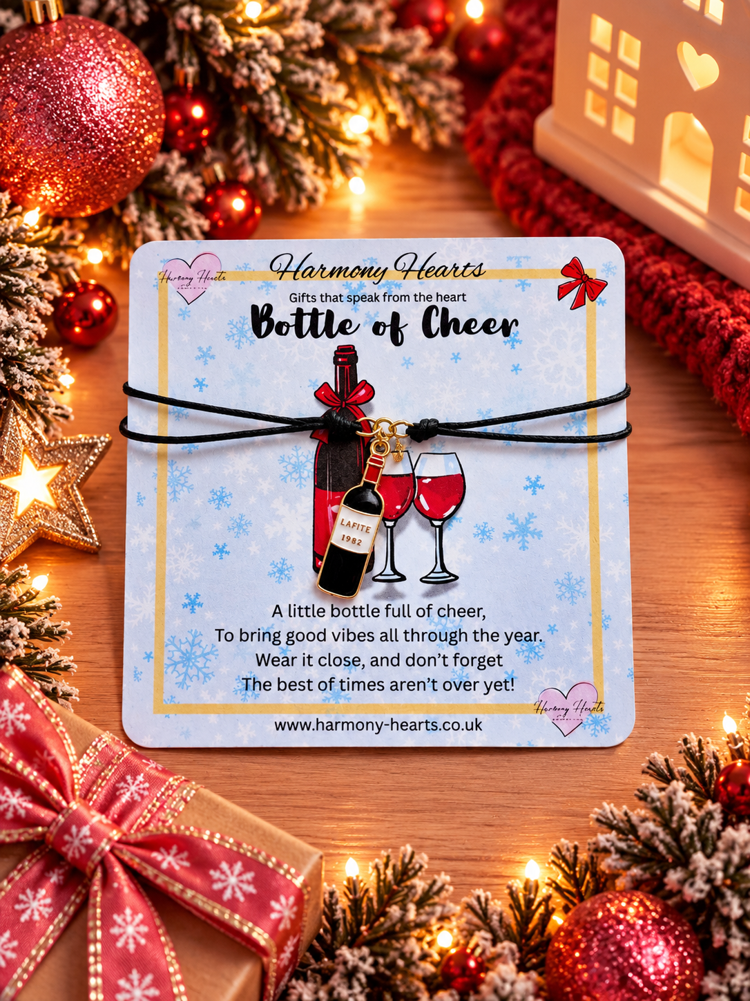 A Christmas-themed wine bottle charm bracelet on a light blue card. The bracelet features a black cord and charm shaped like a wine bottle