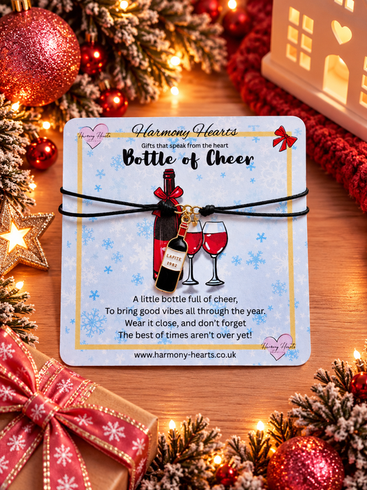 A Christmas-themed wine bottle charm bracelet on a light blue card. The bracelet features a black cord and charm shaped like a wine bottle
