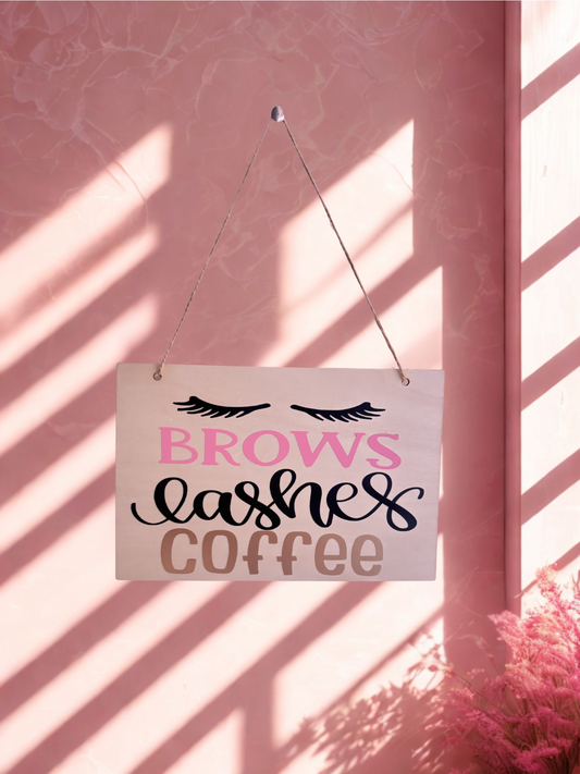 Decorative sign with 'Brows Lashes Coffee' text on a pink background