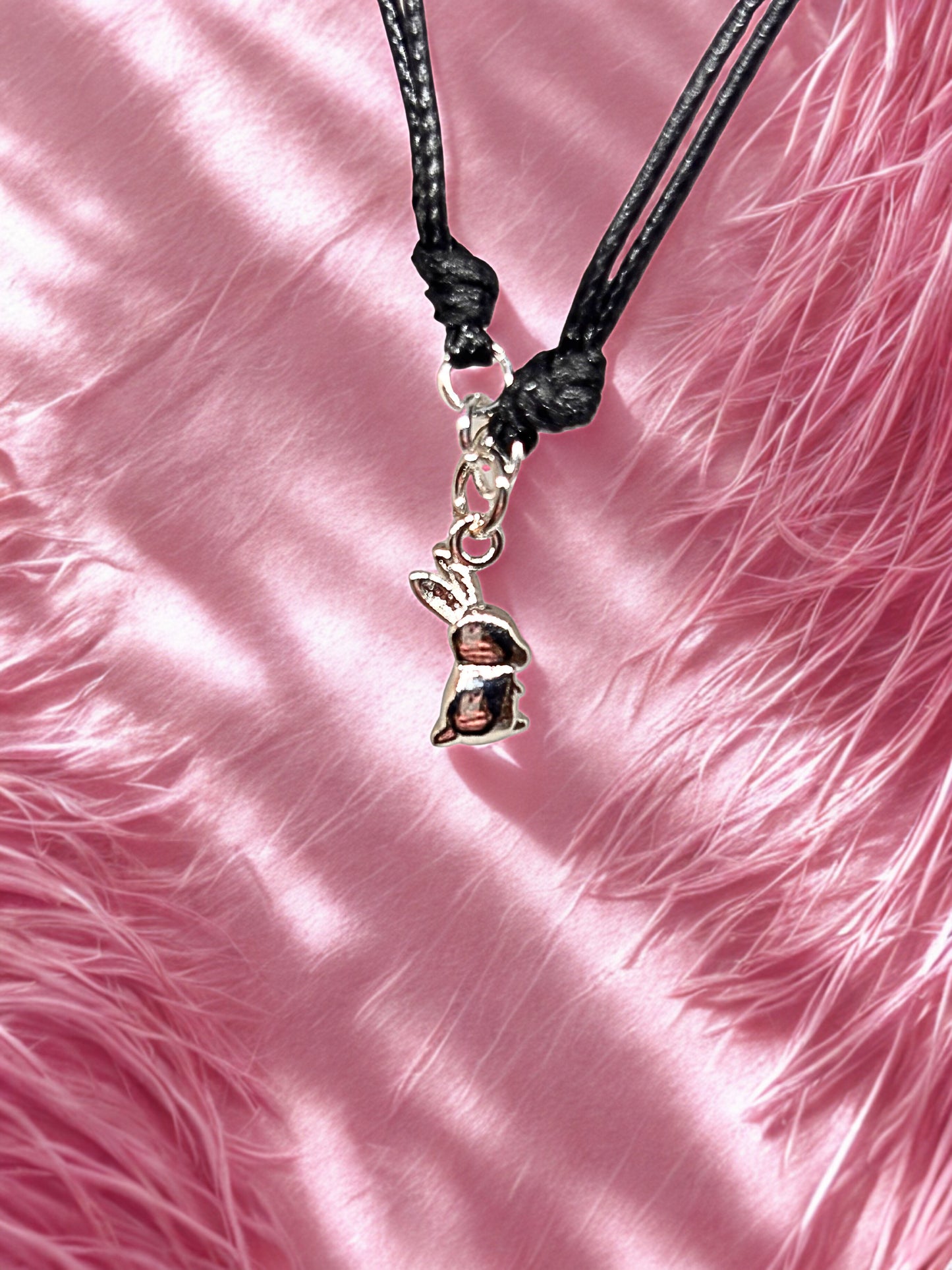 Bracelet with a bunny charm on a pink textured background