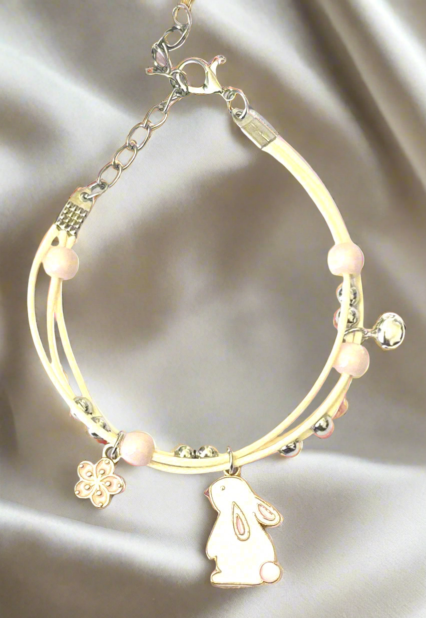 Bracelet with rabbit charm and beads on a soft fabric background