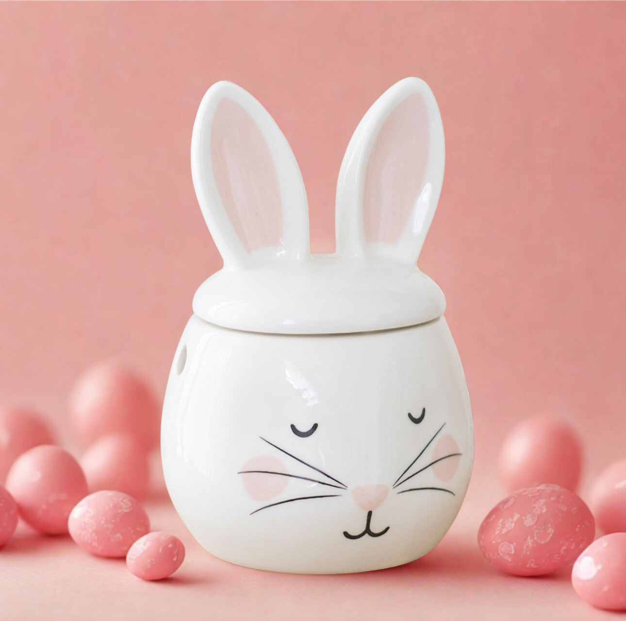 Ceramic bunny oil burner with a lid on a pink background with pink eggs