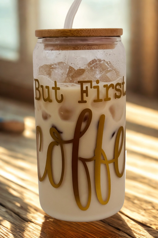 Glass with 'But First Coffee' and iced coffee text on a wooden surface