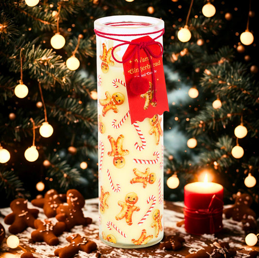 Decorative candle with gingerbread men design in front of a Christmas tree with lights.