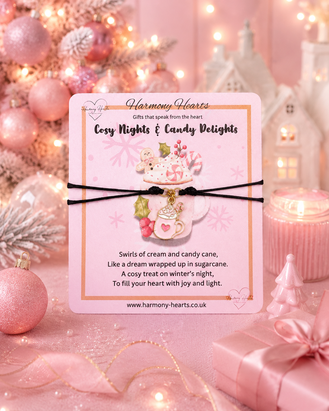 A pink carded gift set from Harmony Hearts featuring a 'Cosy Nights & Candy Delights' charm bracelet. The card showcases a cute illustration of a mug and candy cane, with the actual charms hanging below: a pink mug with a heart, a pink peppermint candy cane, and a small pink heart charm.