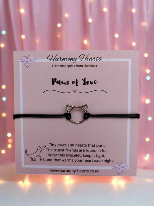 Cat-shaped bracelet on a 'Harmony Hearts' card with a pink background and blurred lights.