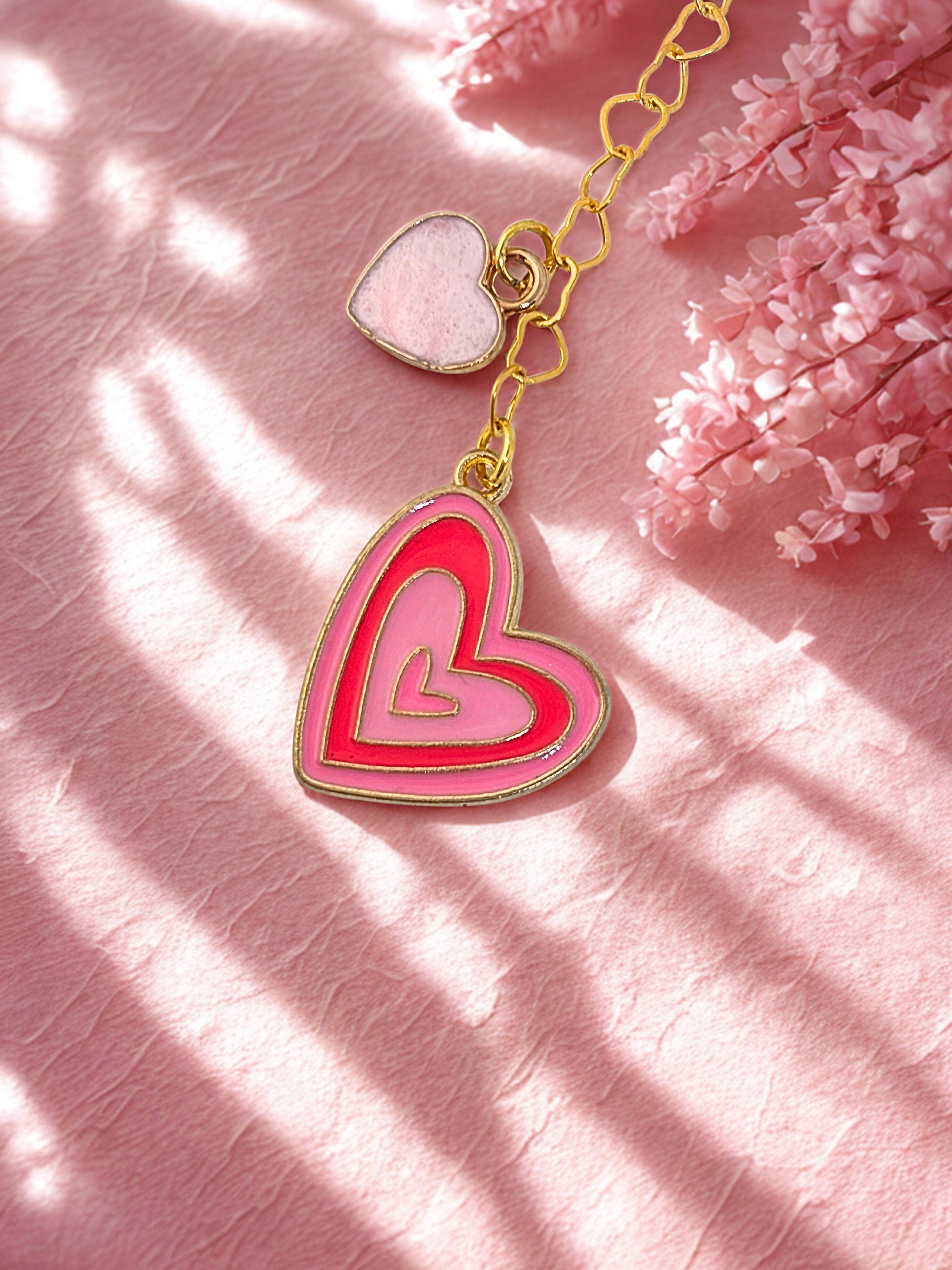 Heart-shaped keychain on a pink textured surface with floral elements