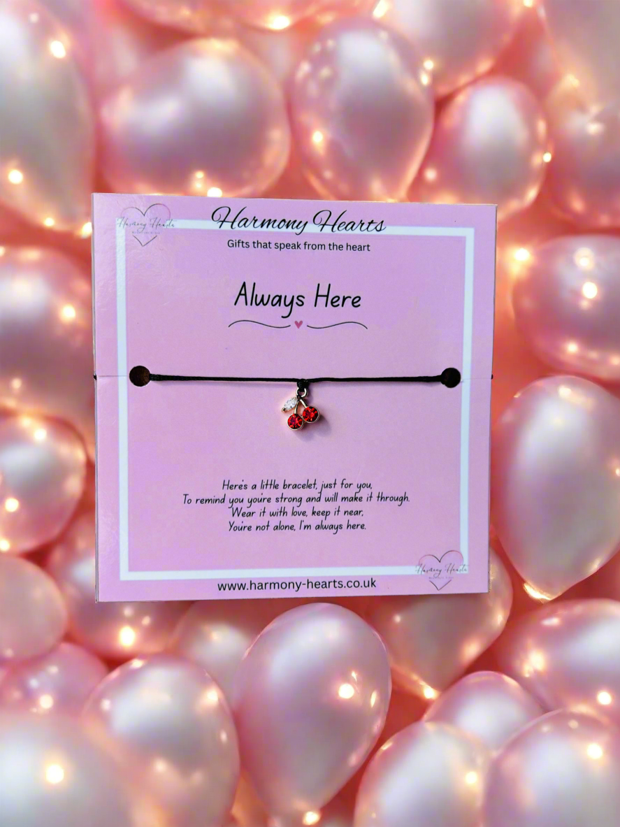 Bracelet on a pink card with 'Harmony Hearts' branding, surrounded by pink balloons and lights.