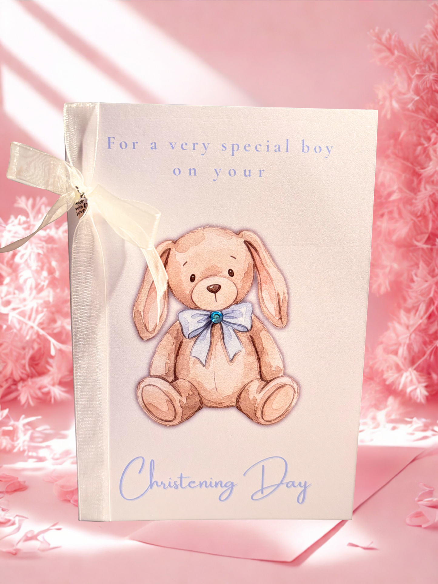 Christening card with a teddy bear illustration and text on a pink background