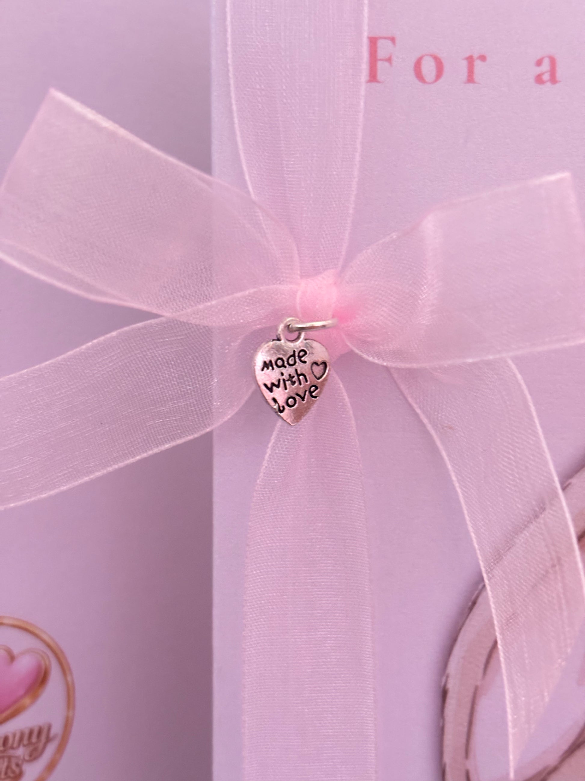 Pink bow and 'Made with Love' charm on a pink background