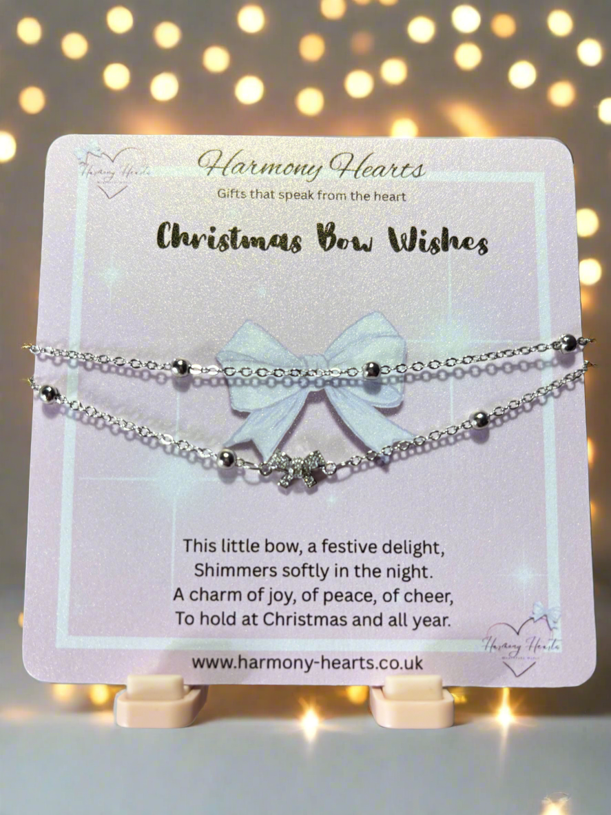Bracelet with bow charm on a 'Harmony Hearts' card with decorative lights in the background