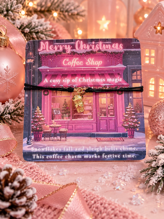 A Christmas-themed coffee shop card with a black cord bracelet featuring a gold coffee cup charm, styled with festive holiday decorations including pink ornaments, pine branches, and warm lights.