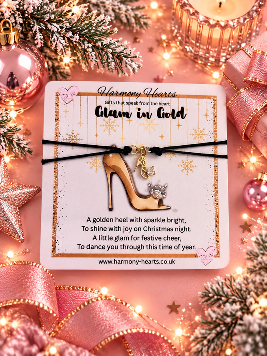 A holiday-themed gift card featuring a charm bracelet with a gold high heel and crystal accent, surrounded by festive decorations like pink ribbons, lights, and pine branches.
