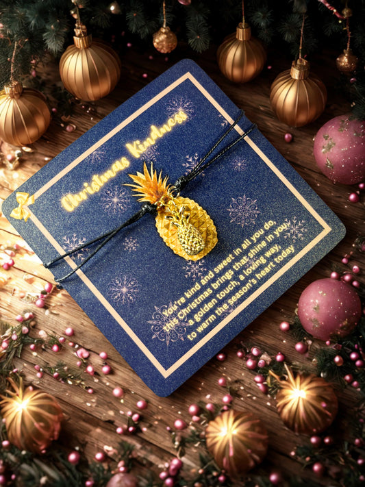 Blue card with gold text and pineapple charm on a festive background with Christmas decorations.
