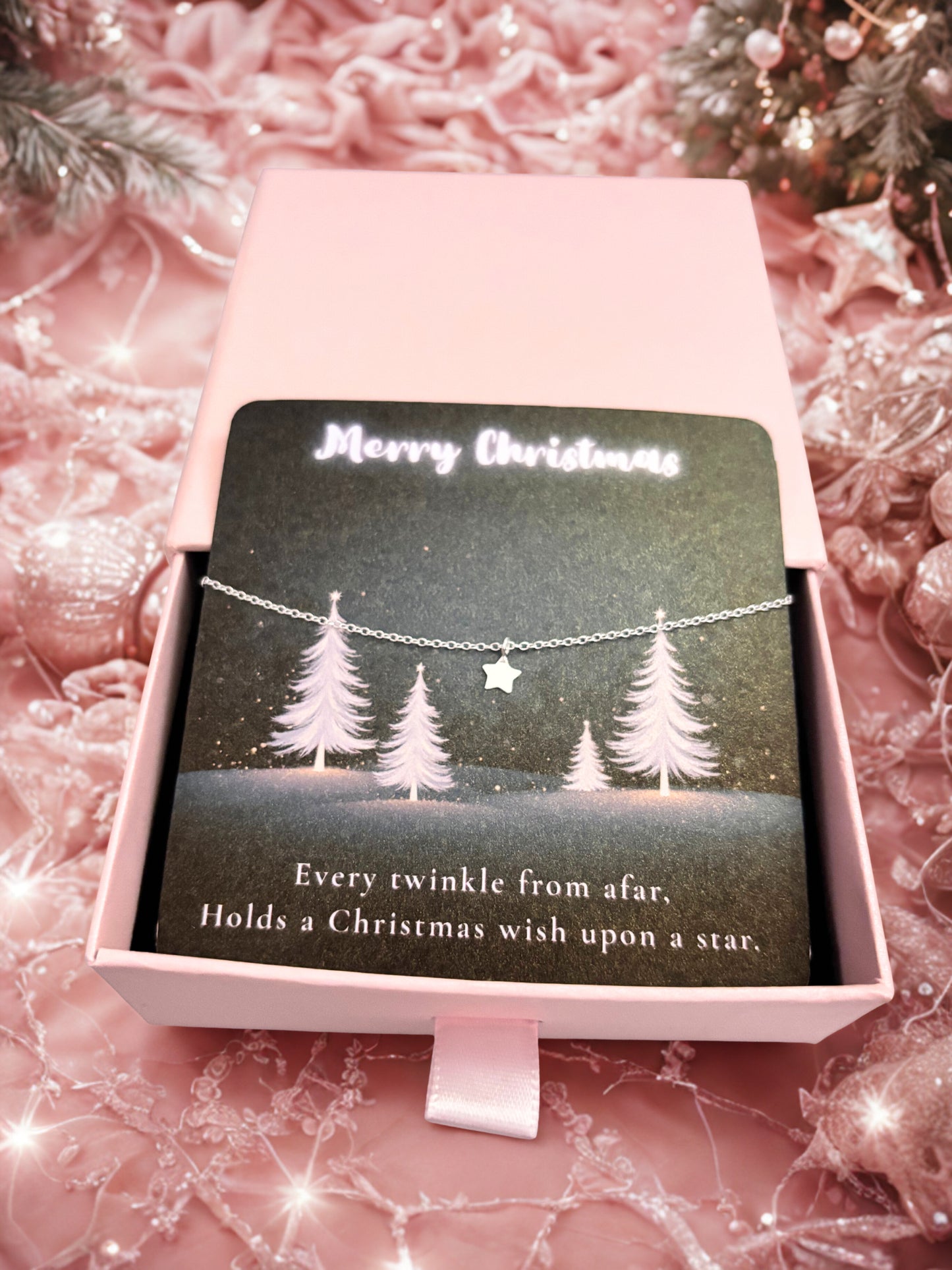 Silver star bracelet on a Christmas-themed card with trees and text in a pink box on a festive background