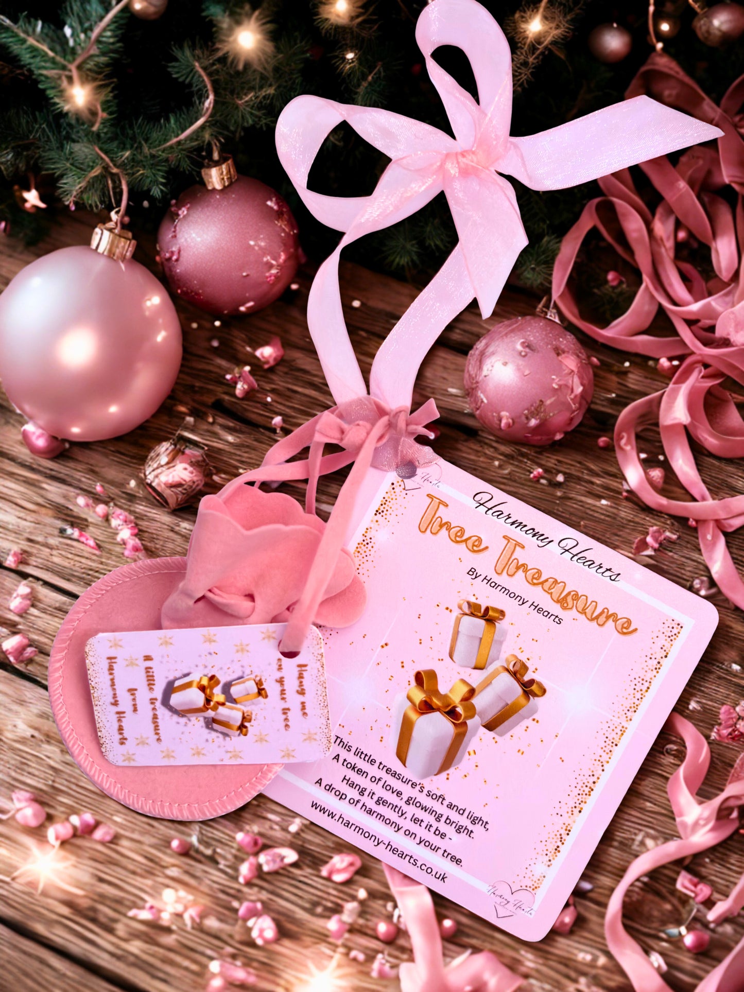 Decorative ornament with pink ribbon and 'Tree Treasure' card on a wooden surface with Christmas decorations.