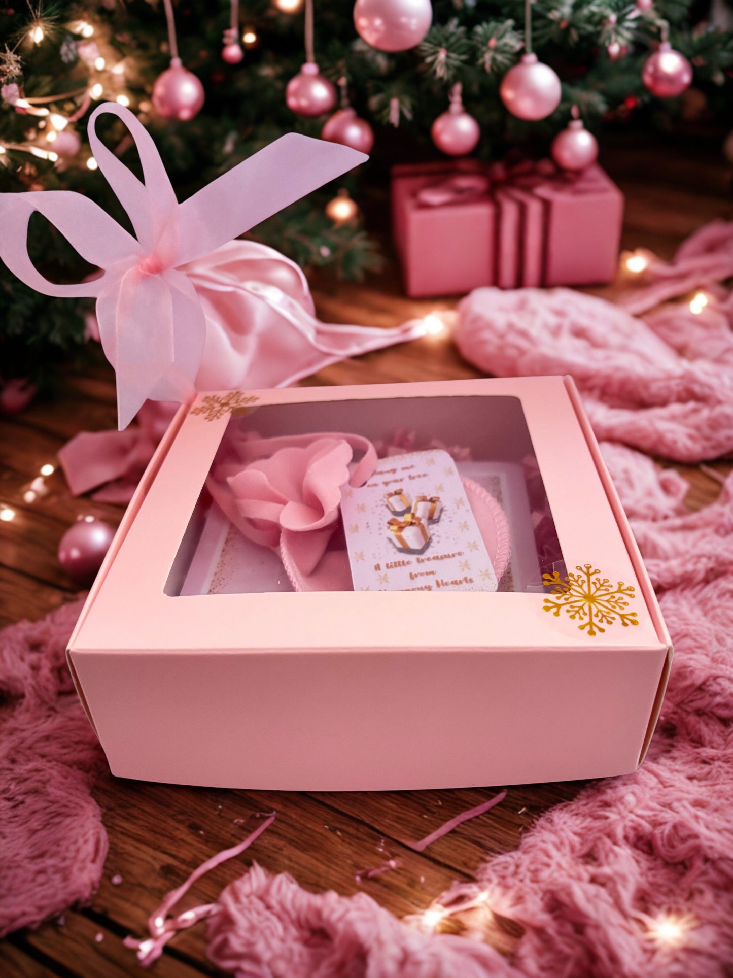 Pink gift box with a bow, and a card inside, set against a festive background with Christmas decorations.