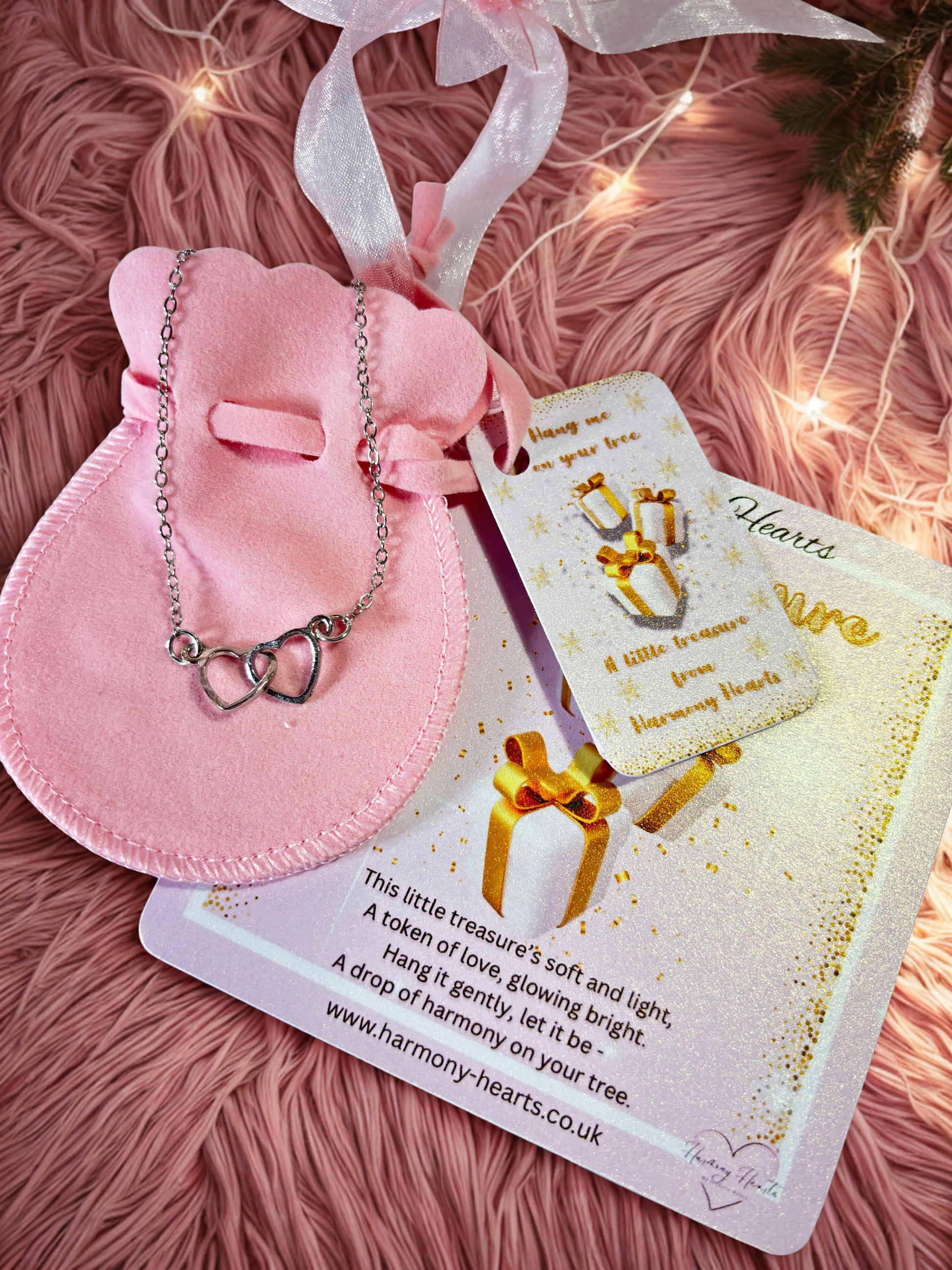 Silver heart bracelet on a pink pouch with Harmony Hearts card under a Christmas tree