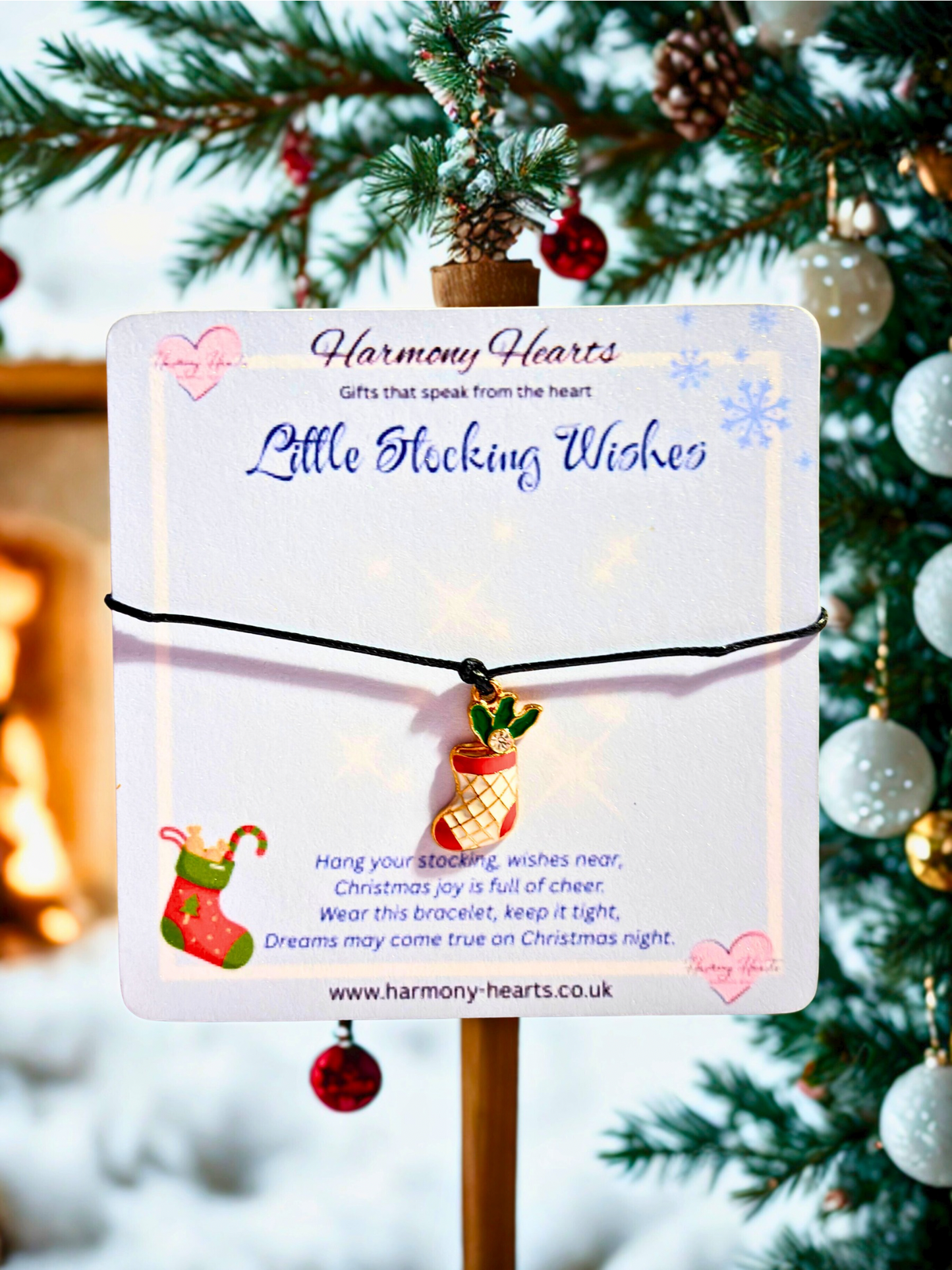 Christmas-themed bracelet with a stocking charm on a card, set against a festive background.