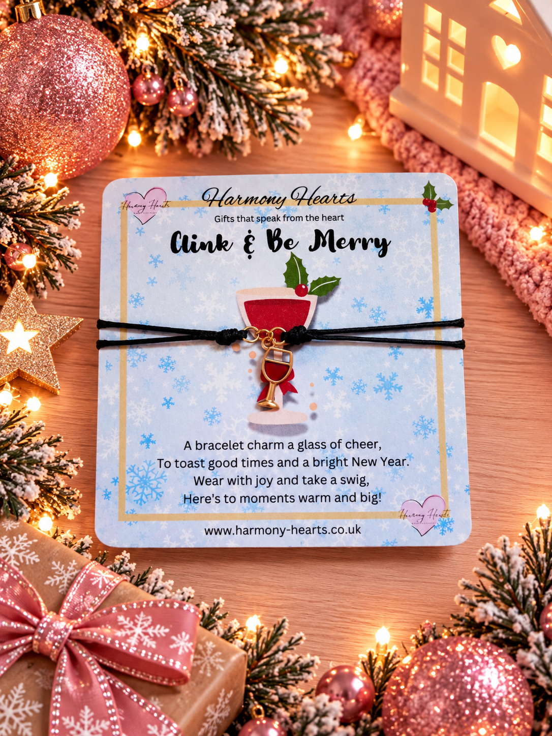 A festive Christmas bracelet with a wine glass charm by Harmony Hearts, displayed on its original light blue holiday-themed backing card. The charm depicts a glass of cheer with red and white liquid, a gold rim, and a red bow.