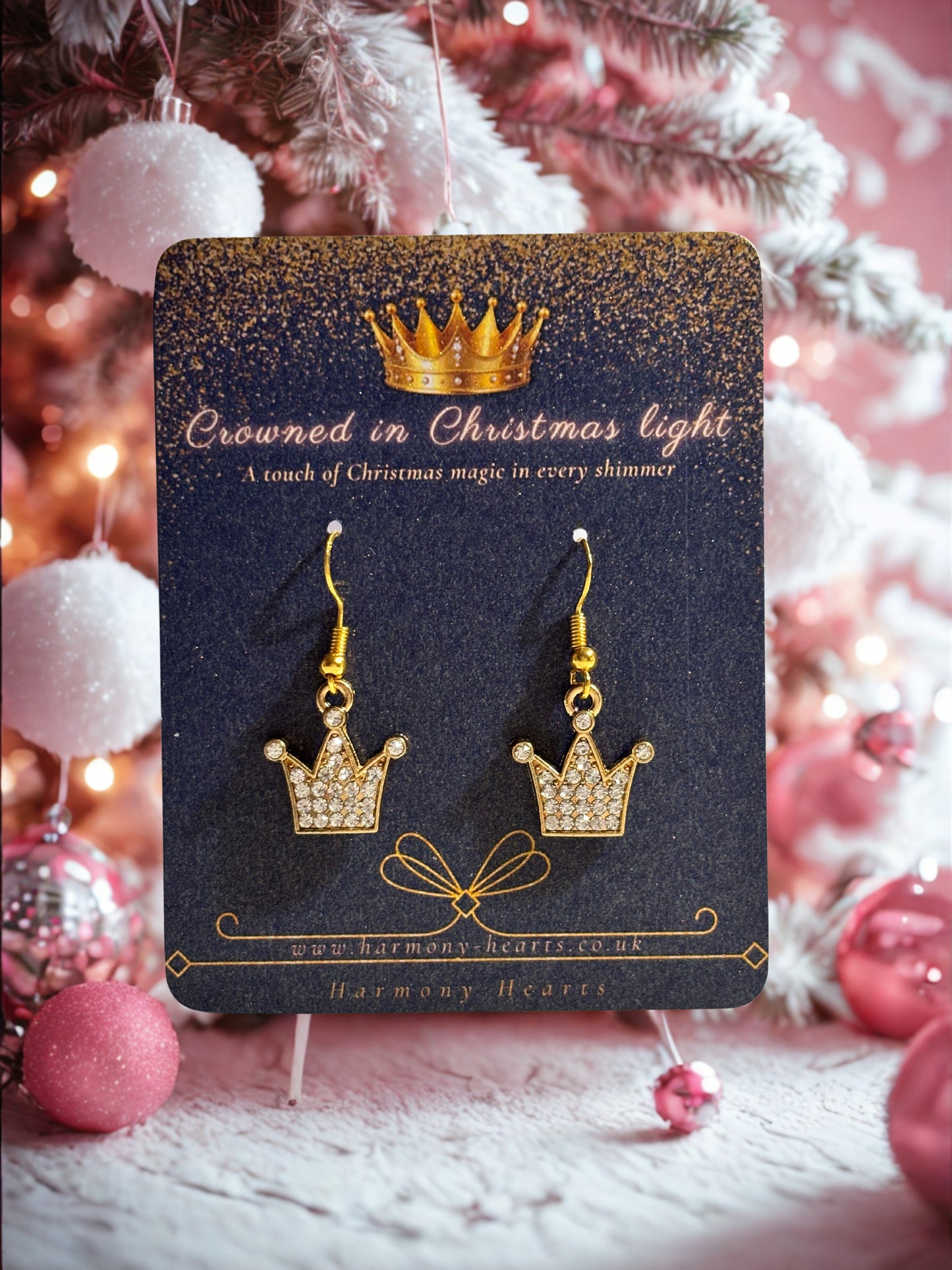 Gold crown earrings on a decorative card with Christmas decorations in the background