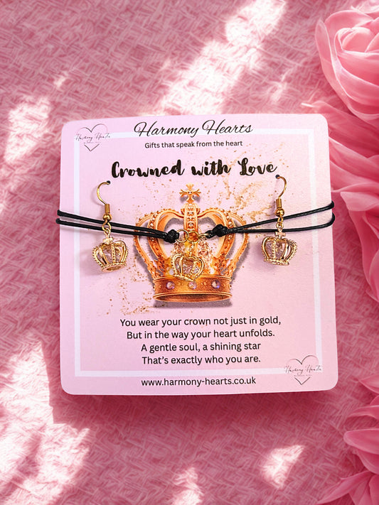 Gold crown-shaped bracelet and earrings on a card with pink flowers in the background