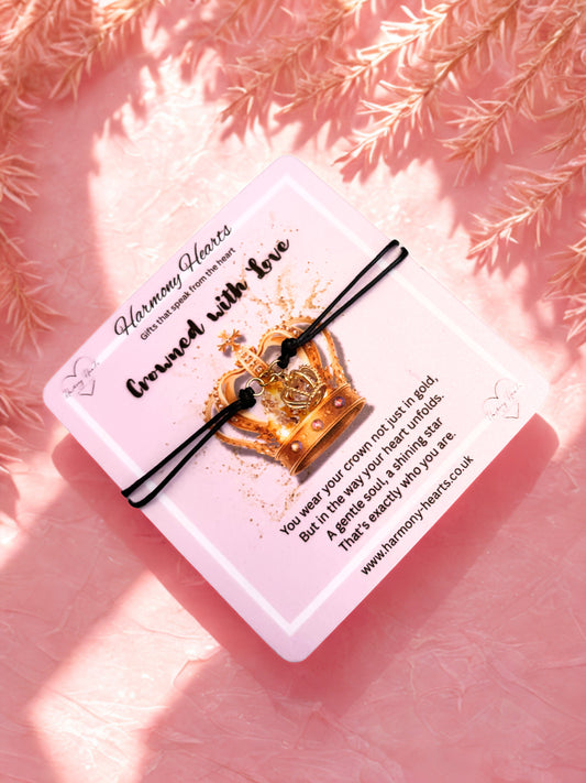 Decorative card with a gold crown charm bracelet and text on a pink background