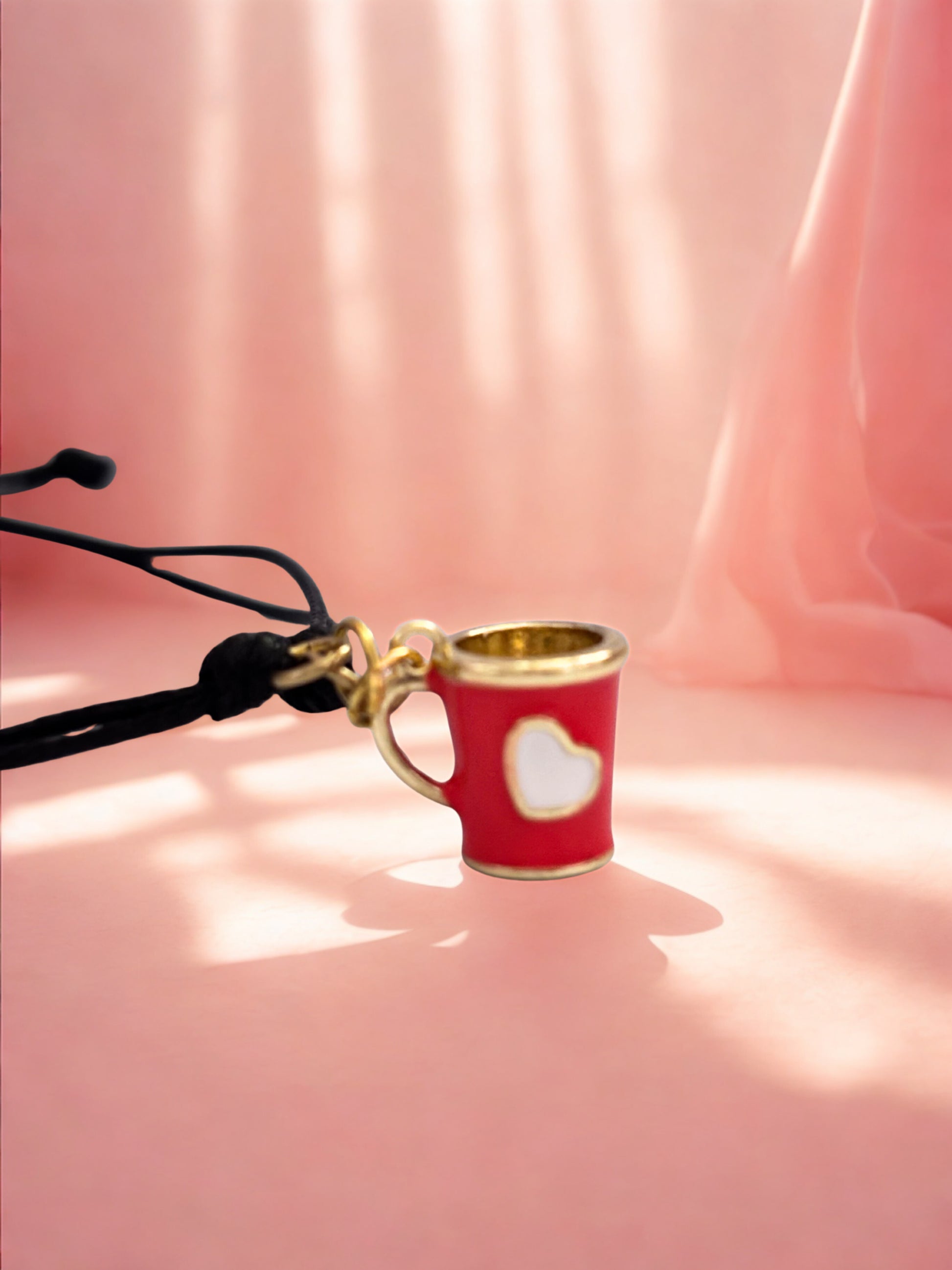 Red cup charm with gold rim on a pink fabric background