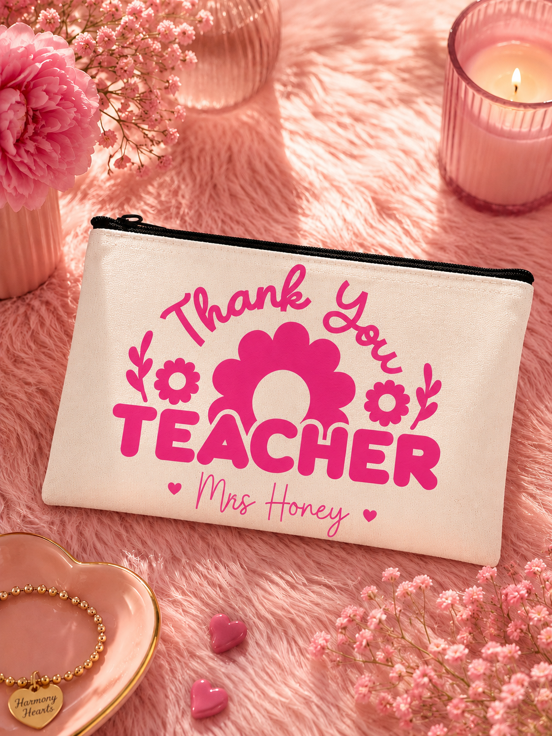 Pouch with 'Thank you teacher' text on a pink surface with flowers and a candle.