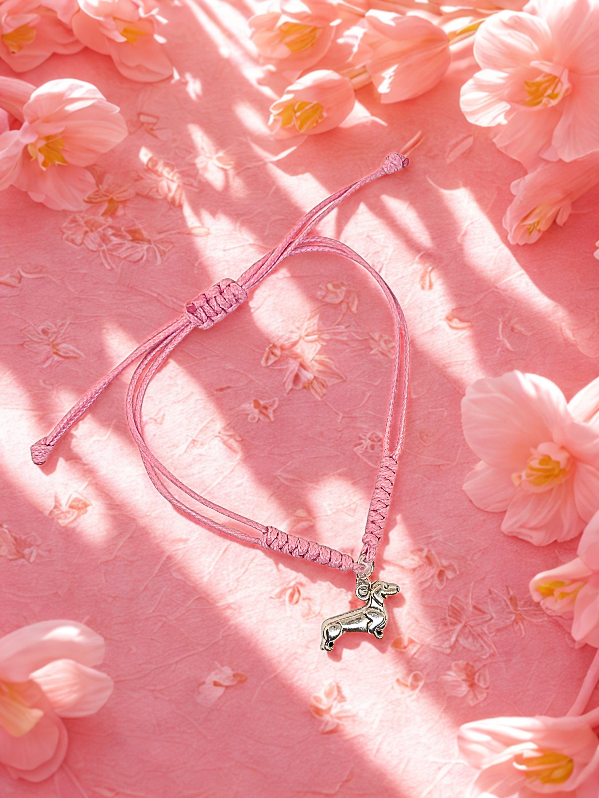 Pink bracelet with a small dog charm on a pink floral background