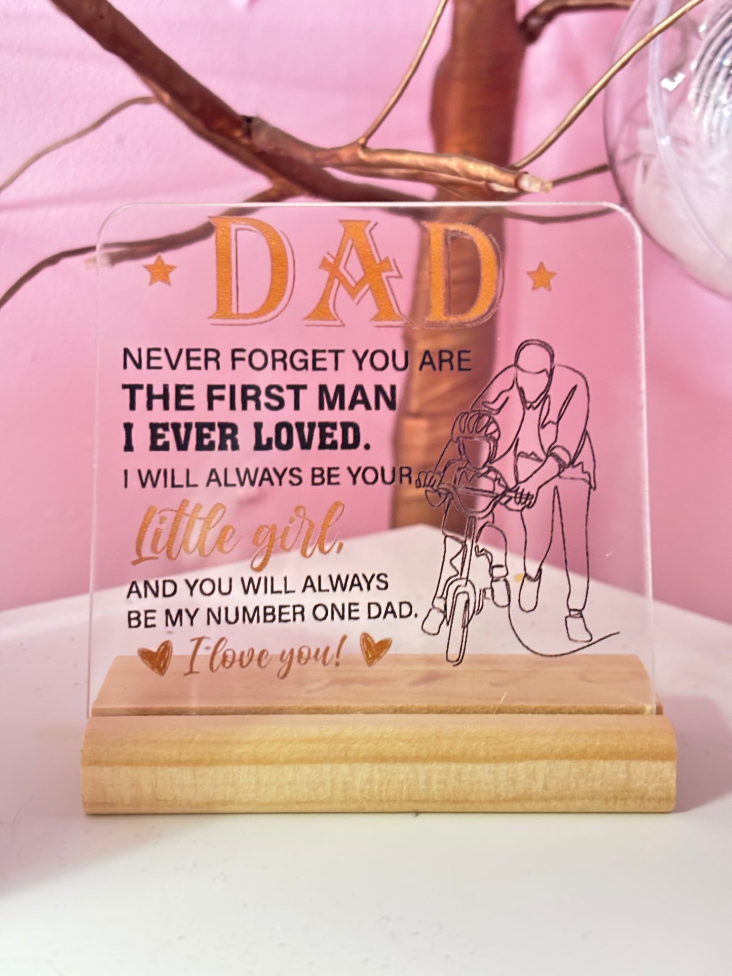 Acrylic plaque with engraved message for a father on a wooden stand, against a pink floral background.