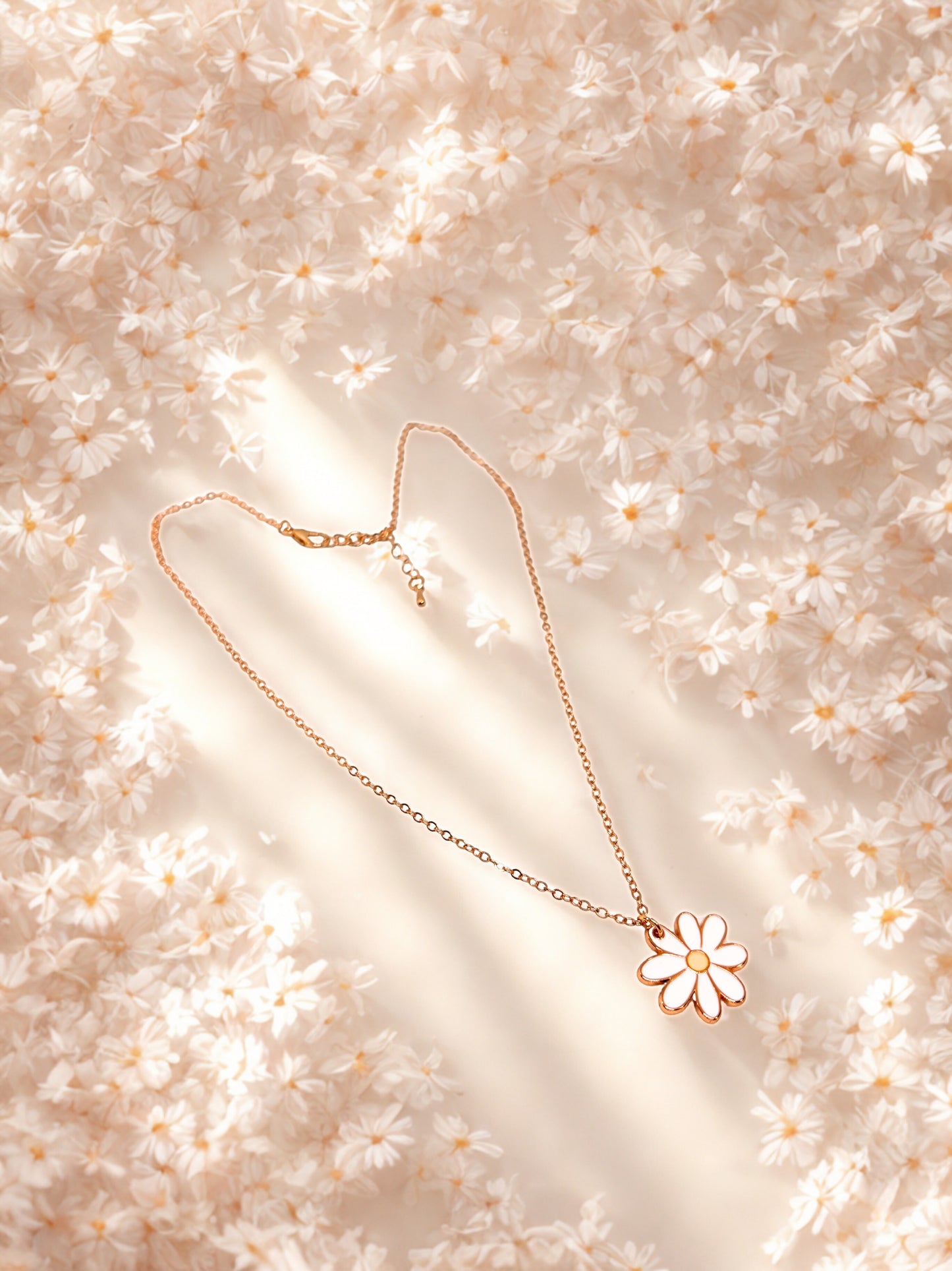 Gold necklace with a daisy pendant on a soft floral background