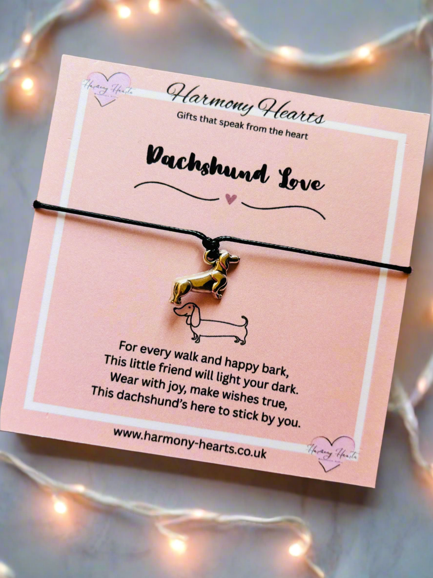 Dachshund-themed bracelet on a pink card with text, surrounded by string lights.