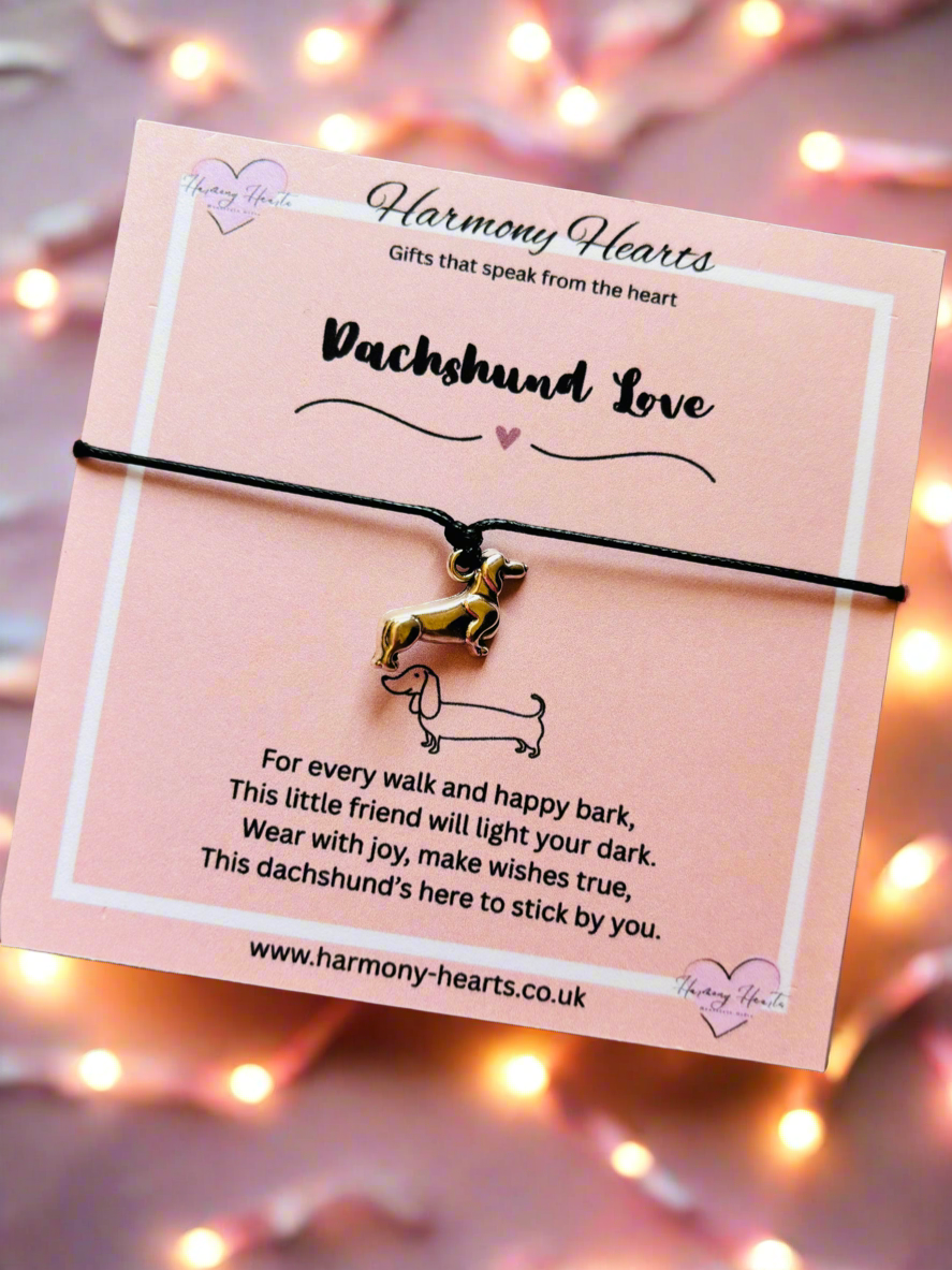 Dachshund-themed bracelet on a pink card with decorative lights in the background