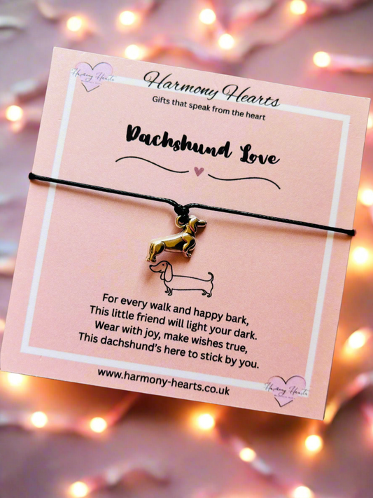 Dachshund-themed bracelet on a pink card with decorative lights in the background