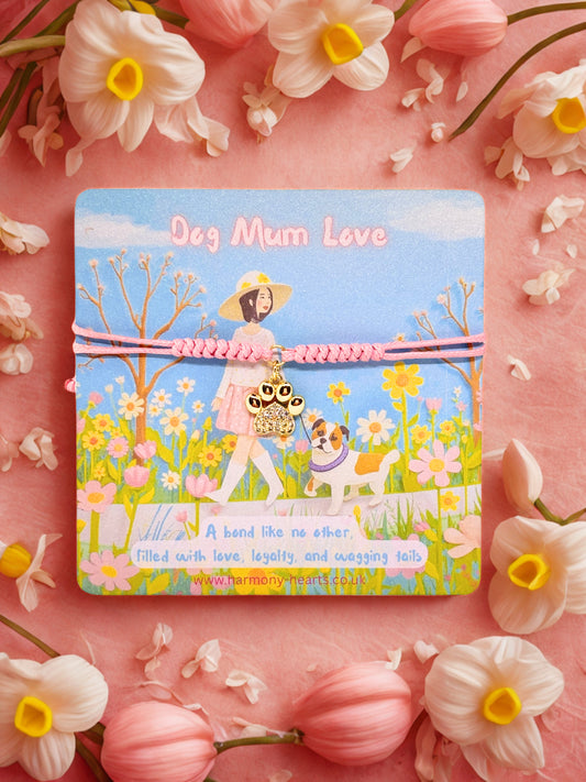 Card with a design of a woman walking a dog in a field, surrounded by flowers on a pink background. With a paw print charm bracelet 