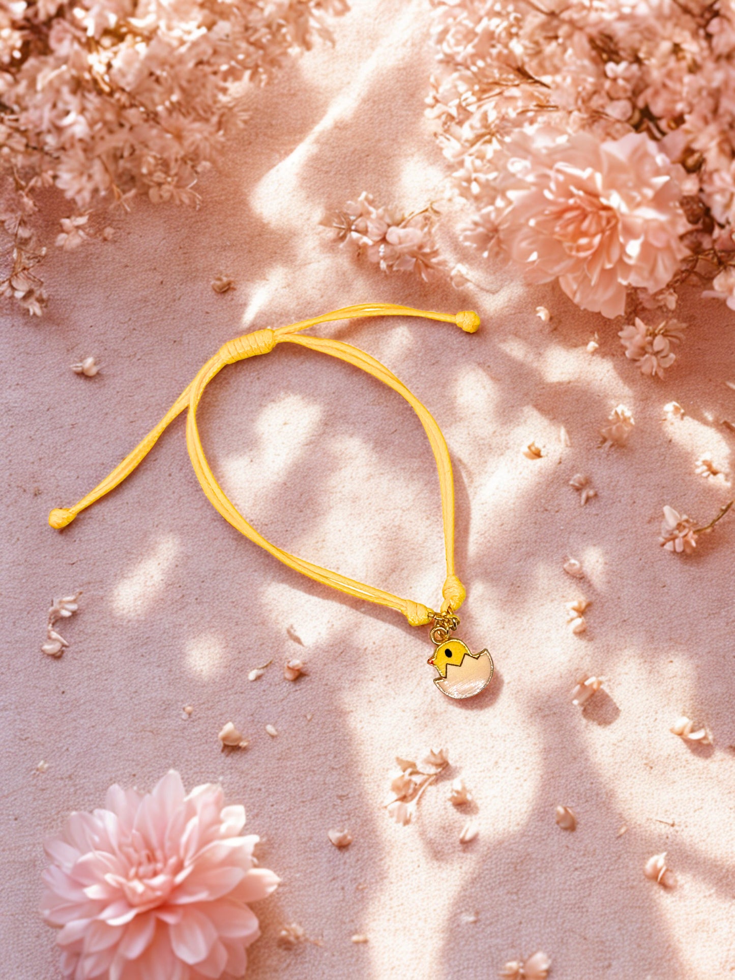 Yellow bracelet with an easter chick charm on a pink floral background