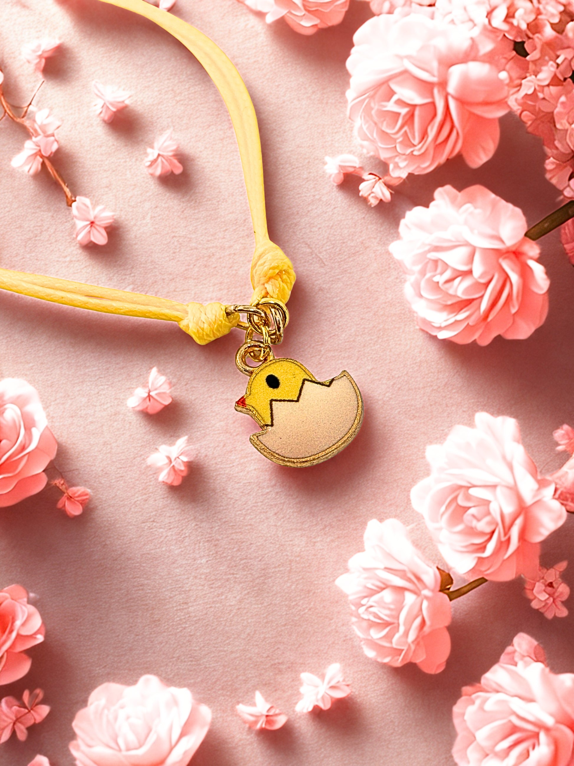 Yellow easter chick charm on a yellow cord with pink flowers on a pink background